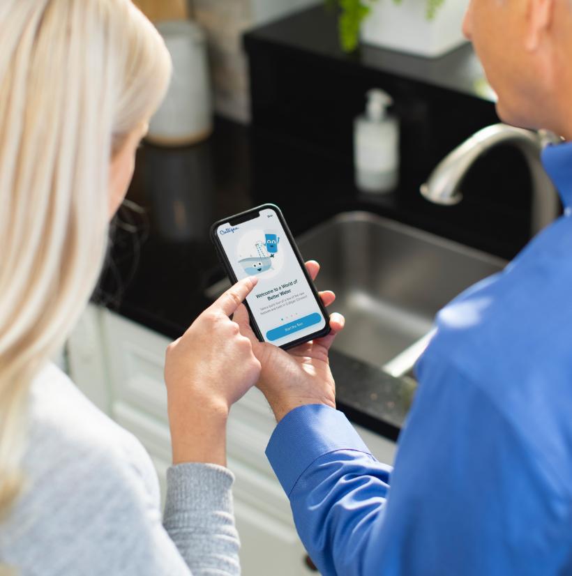 A Culligan rep is helping a homeowner use the app on a smartphone